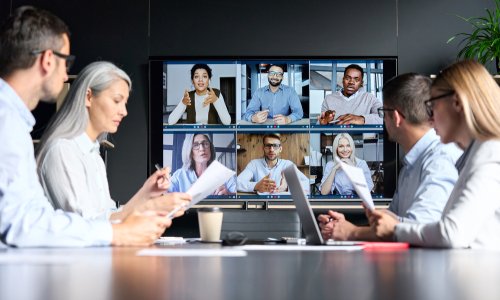 Global corporation online videoconference in meeting room with diverse people sitting in modern office and multicultural multiethnic colleagues on big screen monitor