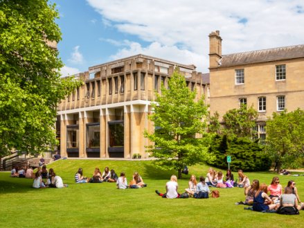 students sitting on the grass on campus